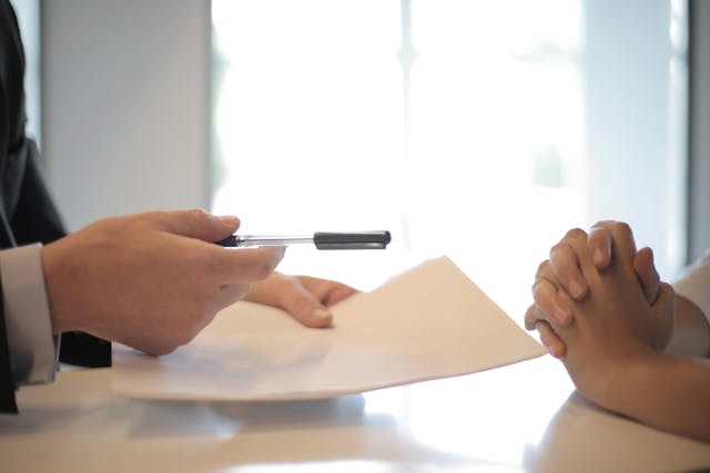 a hand holding a pen giving it to another person